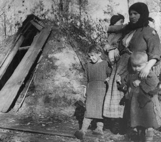 Белорусская крестьянка с детьми у входа в свою землянку. 1942 год. Источник: lhistory.ru