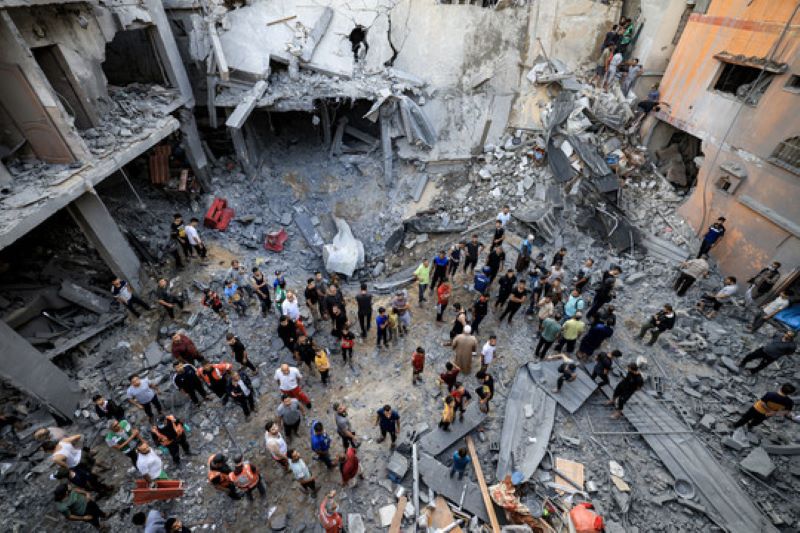 Palestinian civil defence members and locals gather at the site of a building hit by Israeli bombardment in Khan Yunis in the southern Gaza Strip on October 19, 2023. Credit: Mahmud HAMS / AFP